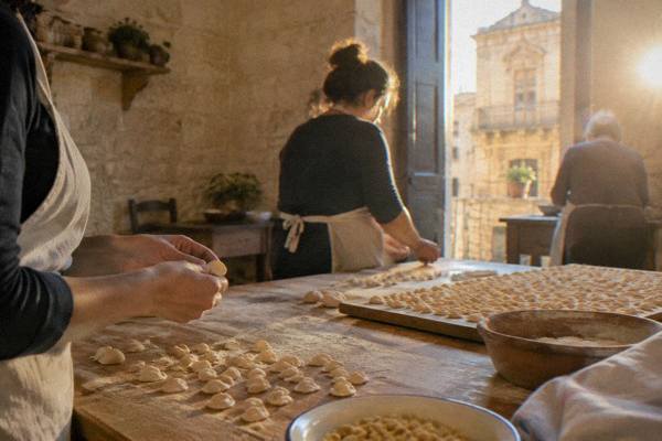 Pasta being rolled on a wooden table in a home kitchen
