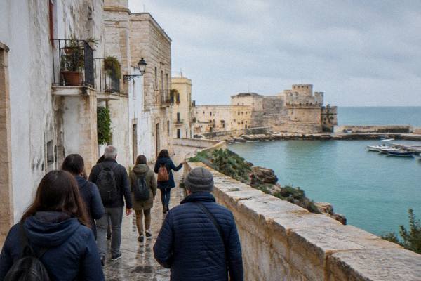 A small group of day visitors following a guide through the narrow whitewashed lanes of a seaside old town, Otranto, Puglia
