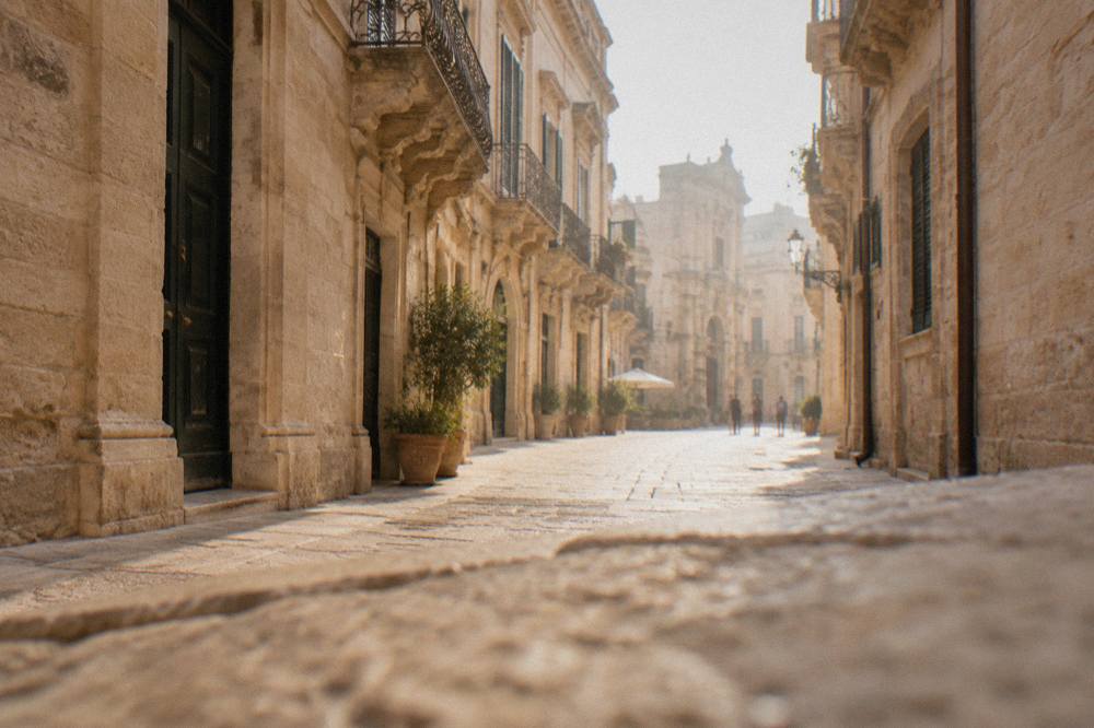A narrow stone street in the old town of Lecce in warm evening light