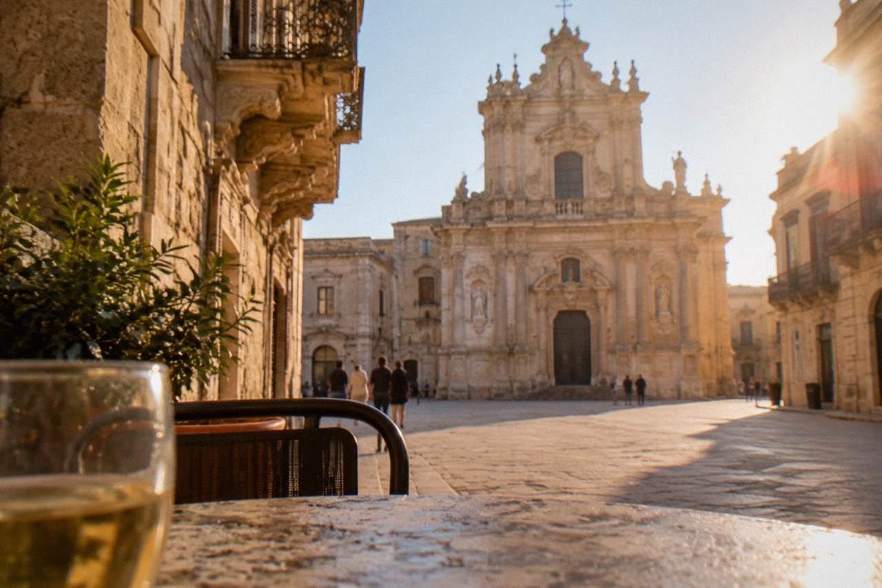 A golden limestone square in Lecce with a baroque church facade glowing in afternoon light