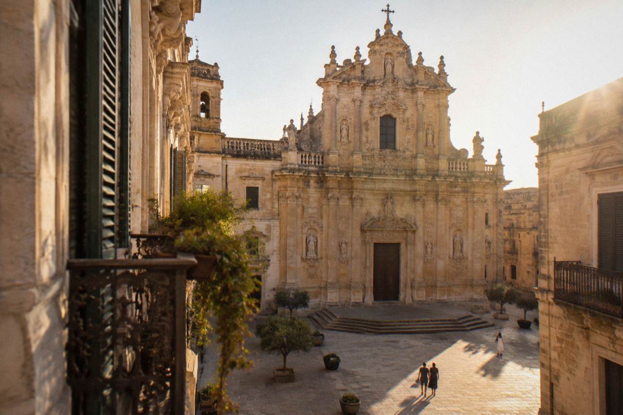The ornate carved facade of a baroque church in Lecce glowing in warm light above a quiet stone square