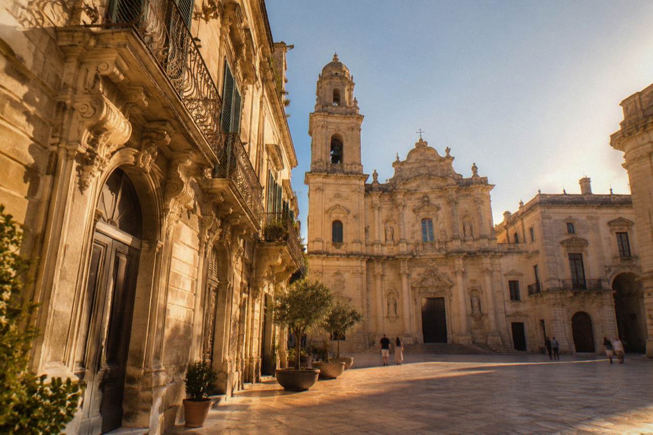 A honey-coloured baroque square in Lecce with carved limestone facades glowing in warm evening light