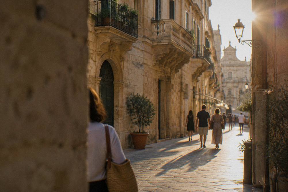 An evening street in Lecce's old town with warm limestone walls, lanterns and people strolling