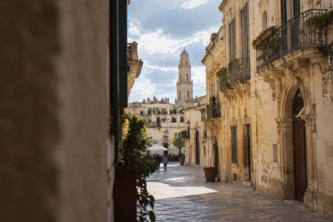 Lecce's limestone old town under a soft winter sky, with the bell tower rising above rooftop terraces.