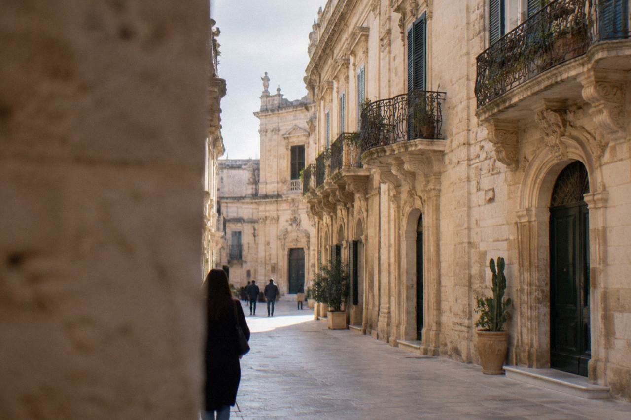Sunlit baroque facades along a narrow limestone street in the Lecce historic centre