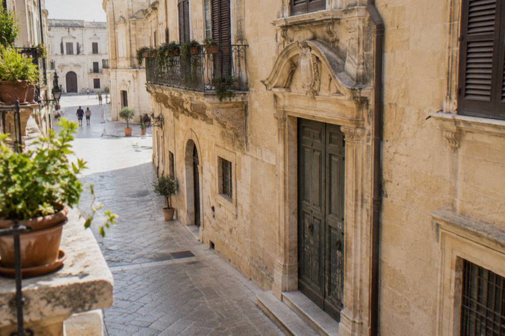 Warm limestone facade with a weathered doorway in a quiet Lecce street