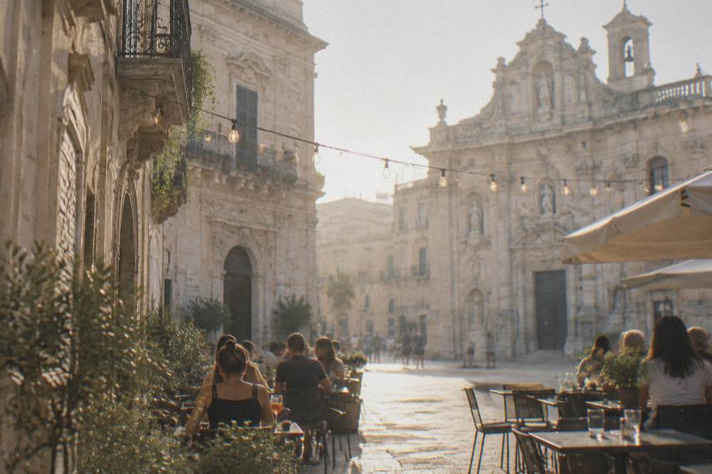 Outdoor tables and string lights at a bar in a Lecce square on a warm evening