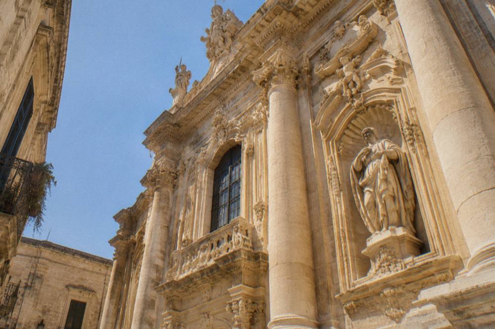 Close view of carved stone details, columns and figures on a golden baroque facade