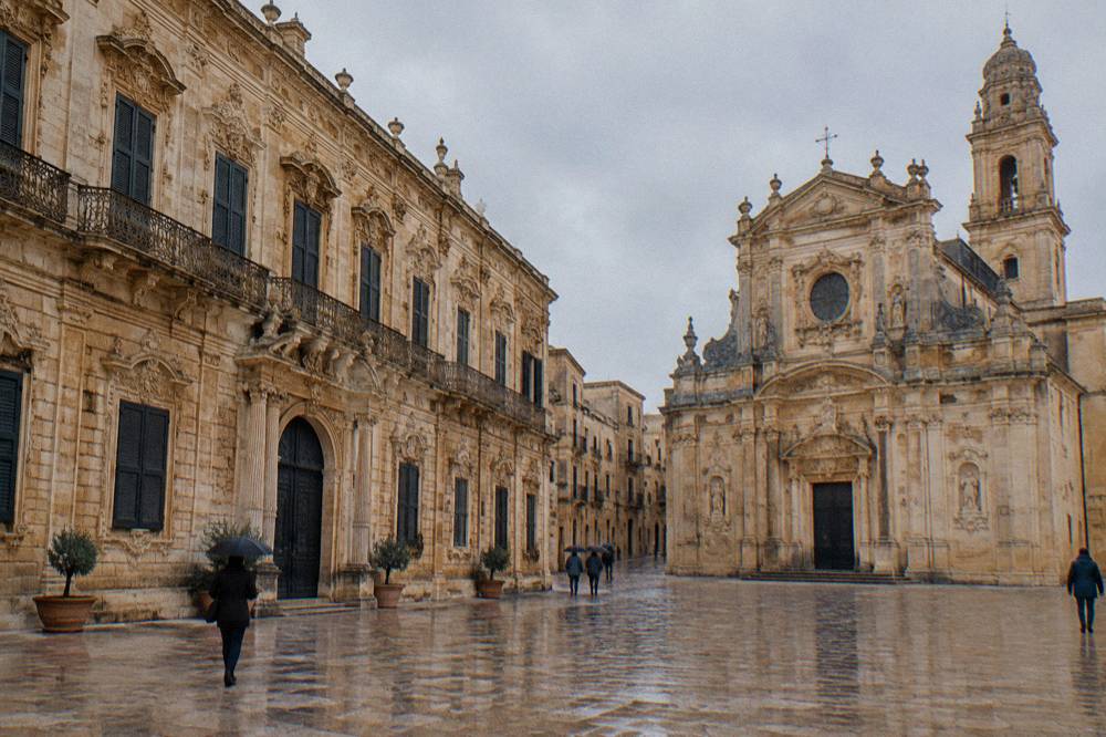 Golden baroque palace facade beside a church in a small square in Lecce