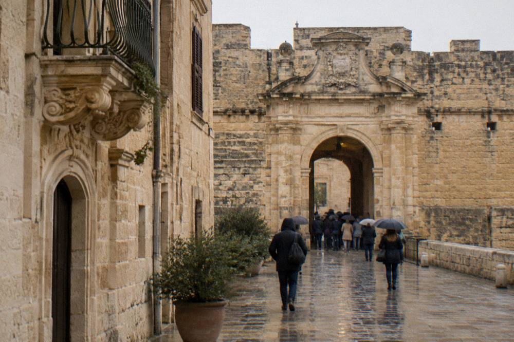 The stone gateway and walls of the castle in Lecce with visitors gathered at the entrance