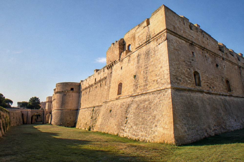 Thick sandstone-coloured castle walls and a dry moat