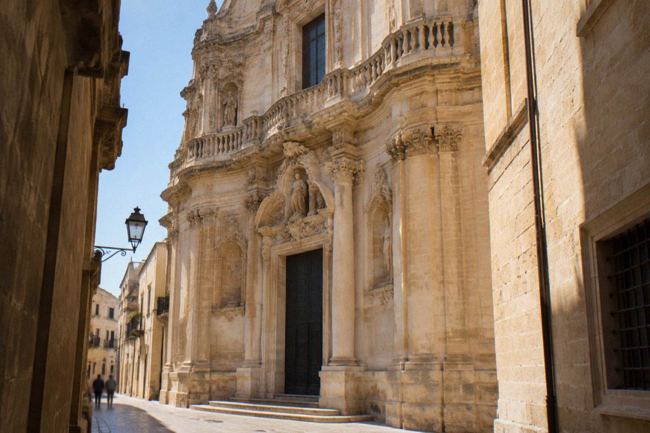 The curved stone facade of the Chiesa di San Matteo in Lecce seen from the narrow street below