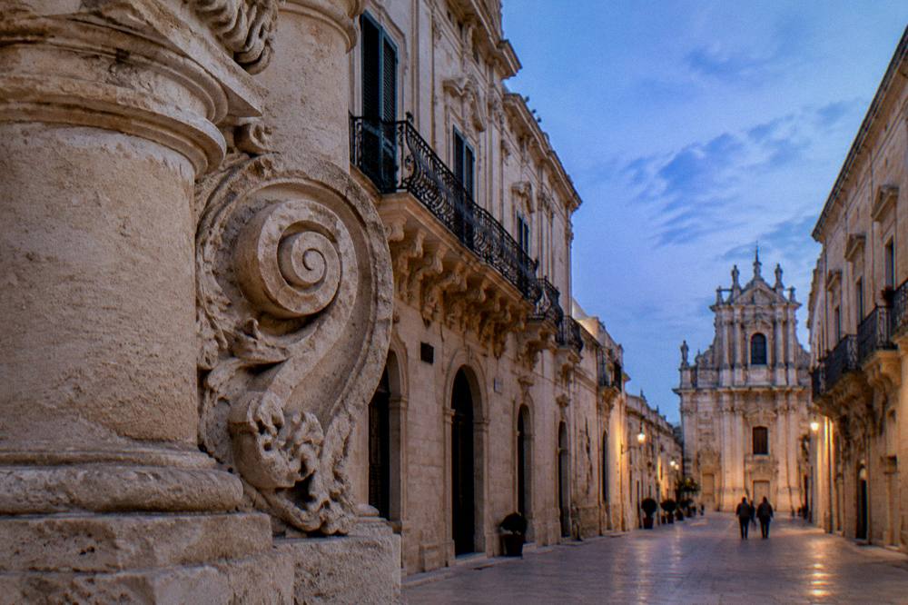 Close view of a carved stone volute and column detail on a Lecce baroque church facade