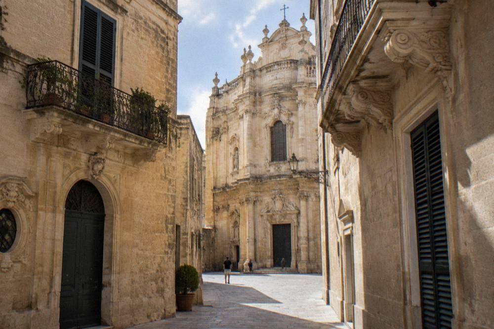 Curved Baroque church facade squeezed between narrow lane walls