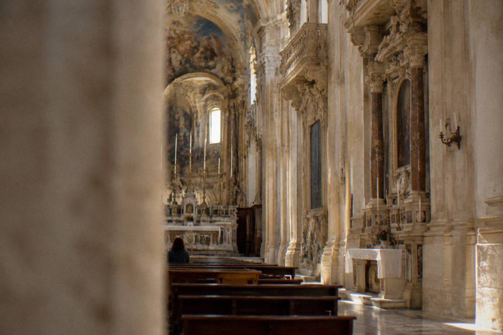 Interior of a baroque church nave with side altars and painted ceiling in Lecce