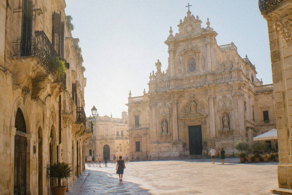 Wide view of a baroque church facade glowing under evening light in Lecce