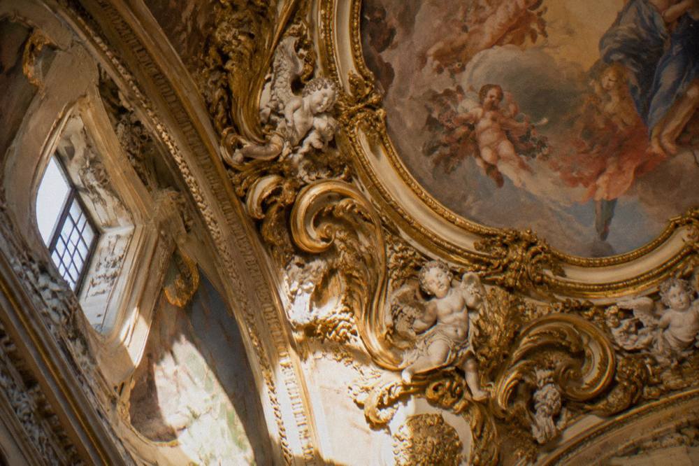 Close view of a gilded ceiling with cherubs and scrollwork ornament