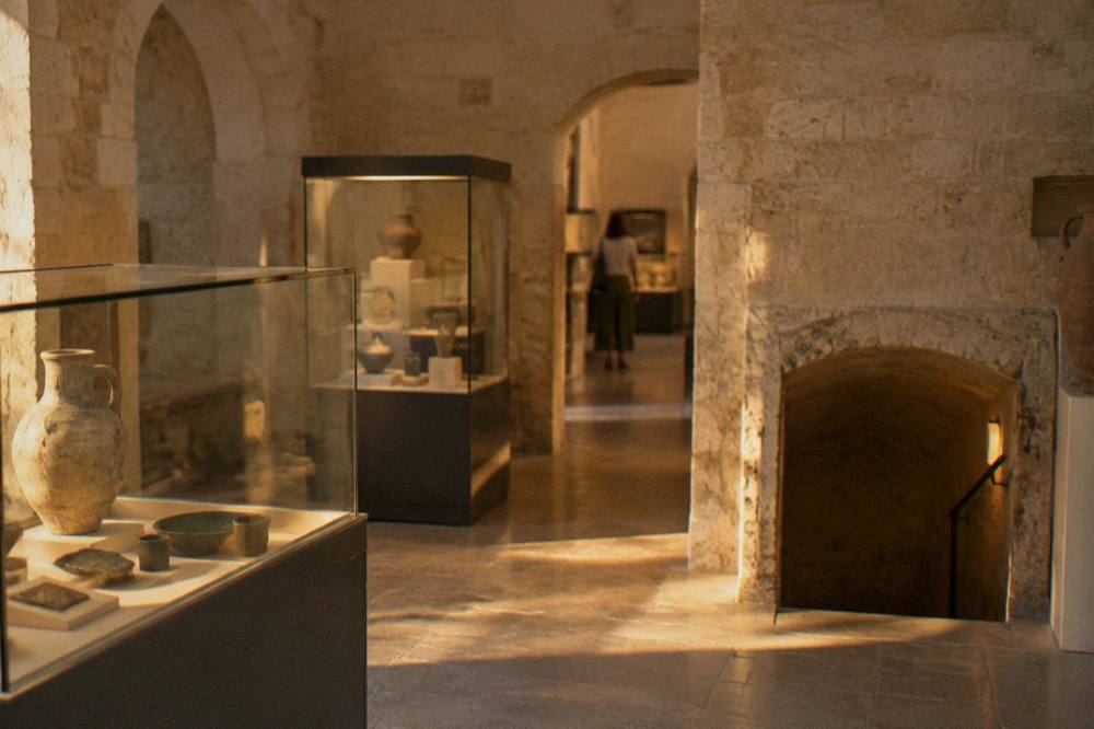 Interior of a small museum with display cases of medieval artefacts lit softly