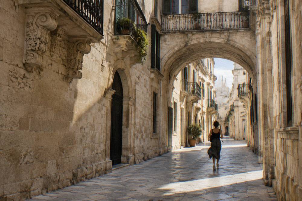 A limestone archway on a narrow lane in central Lecce in afternoon light