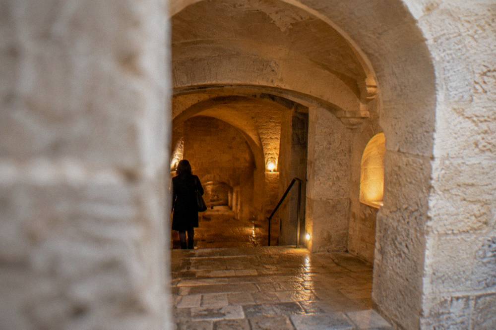 Stone vaulted cellar space with arched niches lit by warm lamps