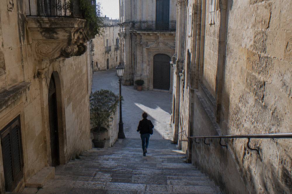 Stone steps descending between old masonry walls into a dim cellar in Lecce
