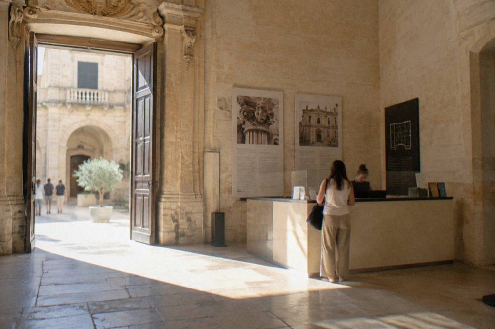 A museum ticket desk in an old Lecce building with stone walls and information panels