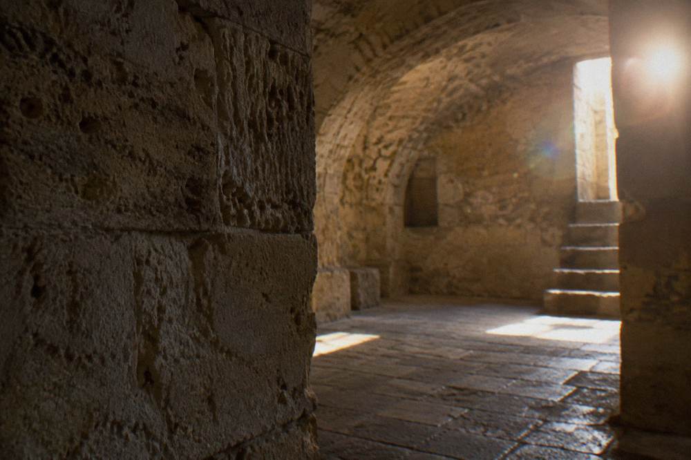 An exposed section of ancient stone masonry and an arch in an underground room in Lecce