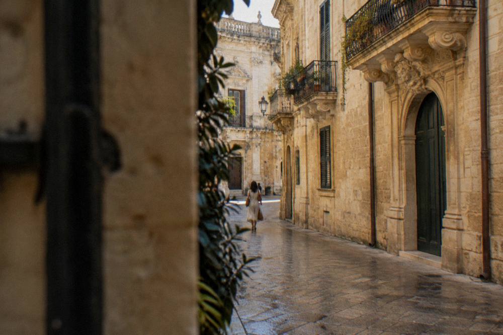 A quiet stone-paved lane in Lecce old town with warm limestone walls in afternoon light