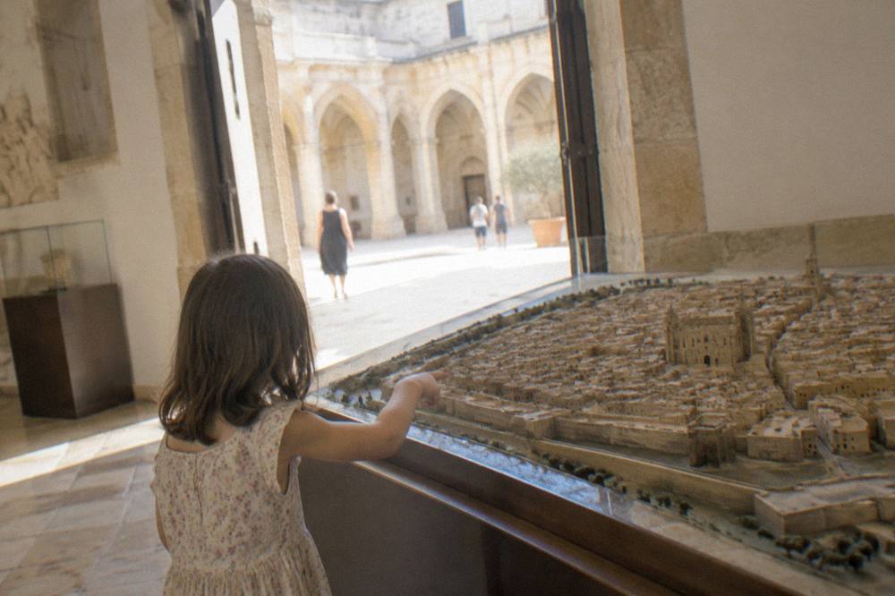Child pointing at a scale model of a historic town in a museum