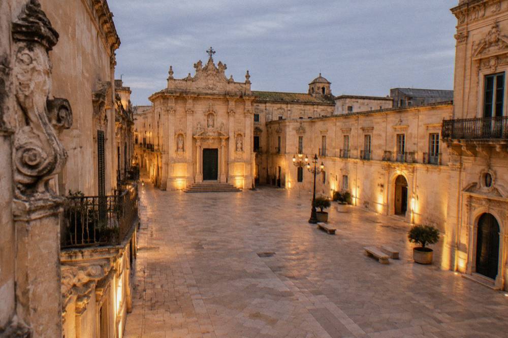 An empty Italian square at dusk with warm light on baroque buildings