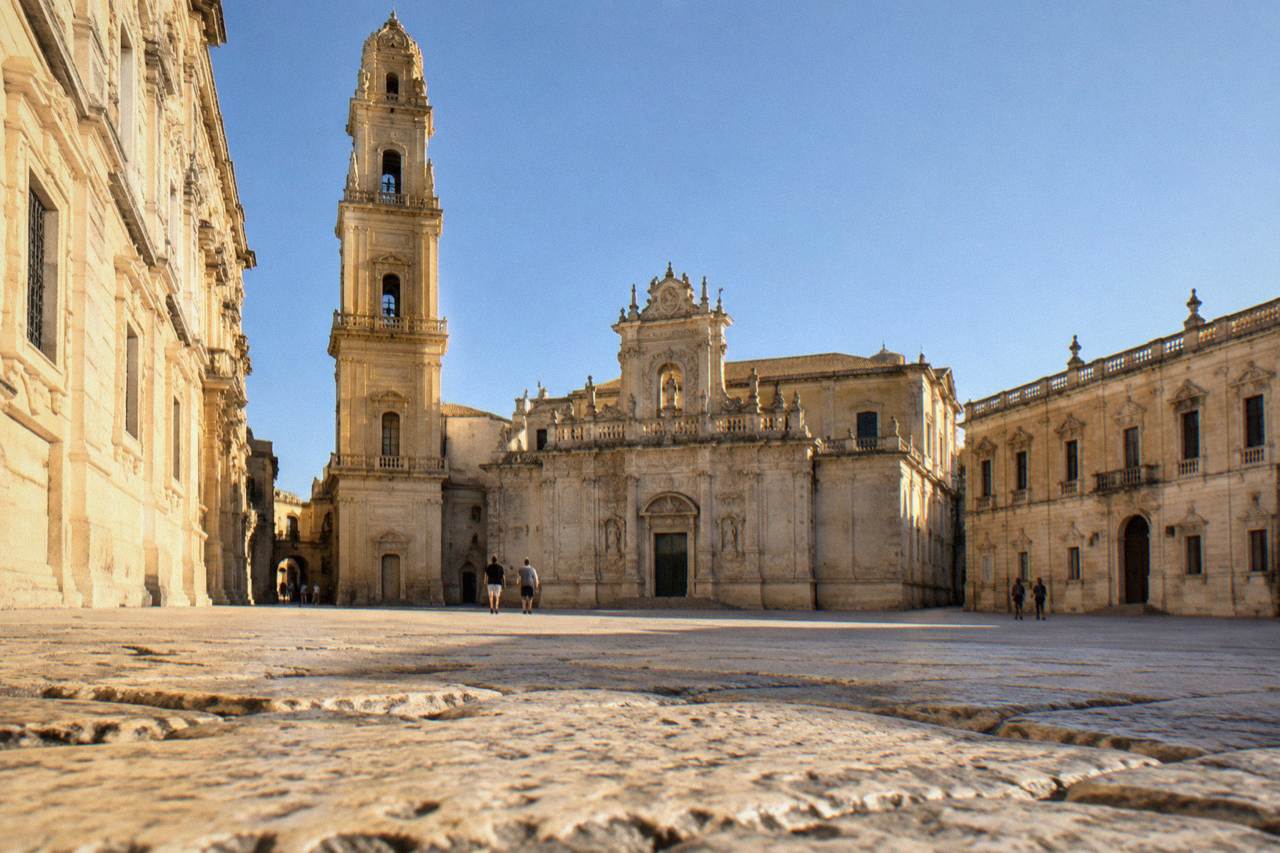 The facade of Lecce Cathedral seen across Piazza del Duomo in late afternoon light