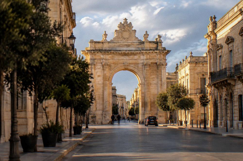 Golden evening light on a carved limestone arch at the end of a city street
