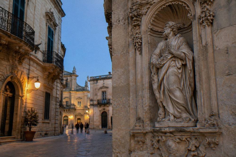 Detail of carved limestone figures in a niche on an old city gate in Lecce