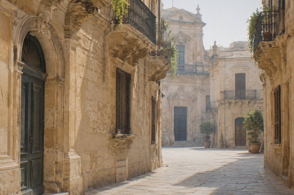 A quiet stone street lined with carved limestone facades in Lecce's old town