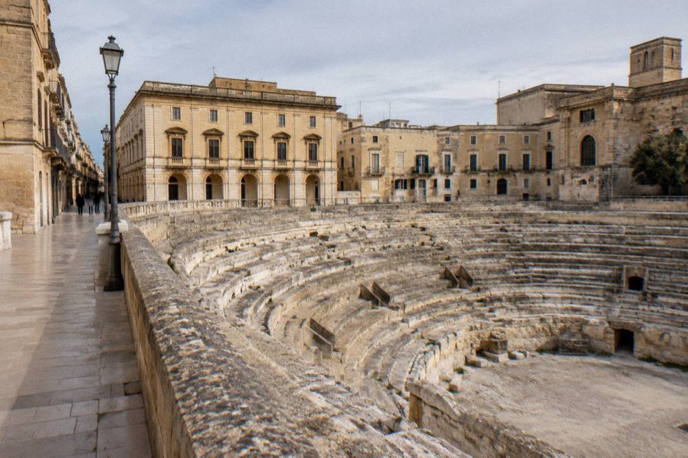A narrow old-town street of warm limestone leading from the main square toward the Roman Theatre district