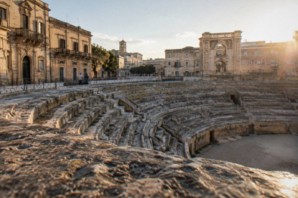 Warm late-afternoon light raking across the stone seating of the Roman arena in Lecce