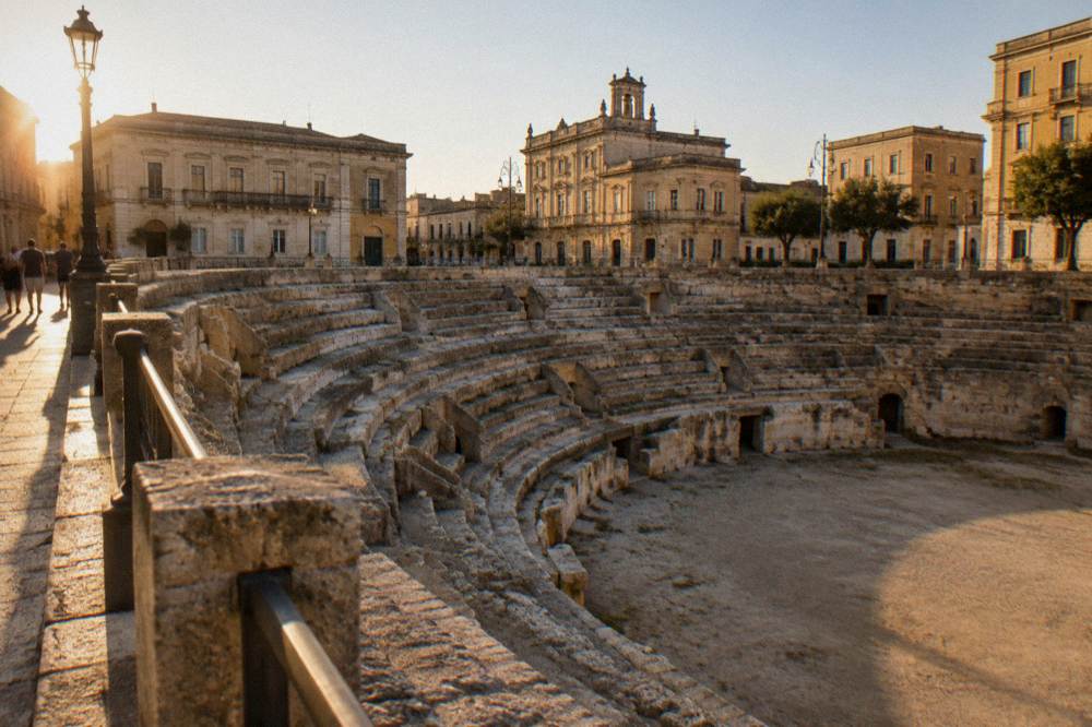Curved tiers of an excavated Roman amphitheatre below street level