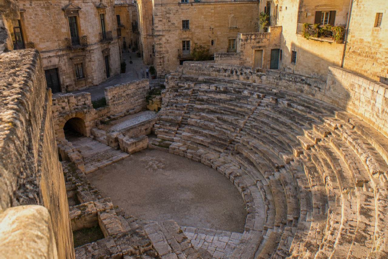 Ancient Roman semicircular theatre steps framed by the walls of surrounding buildings in a narrow Italian street
