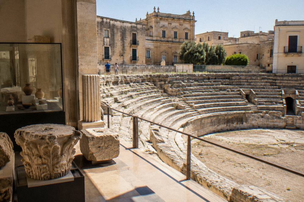 Interior of a small archaeological museum with stone fragments and display cases of Roman finds