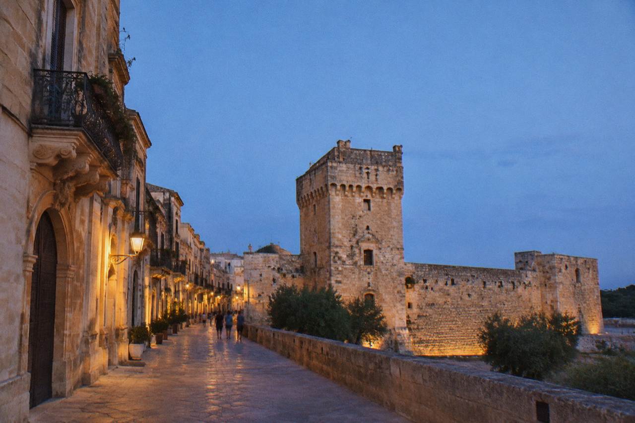 A stone watchtower and defensive wall surrounding a small village in the Salento countryside near Lecce