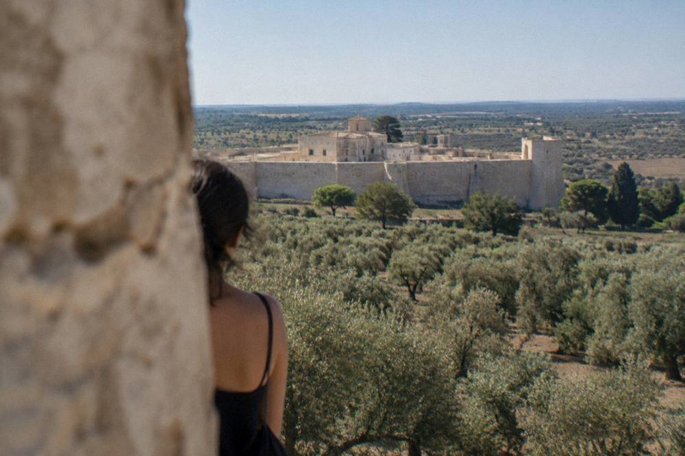 A walled village seen across olive groves with the flat Salento plain stretching to the horizon