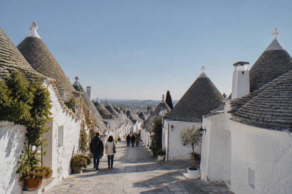 A whitewashed lane of trulli houses with conical roofs in morning light
