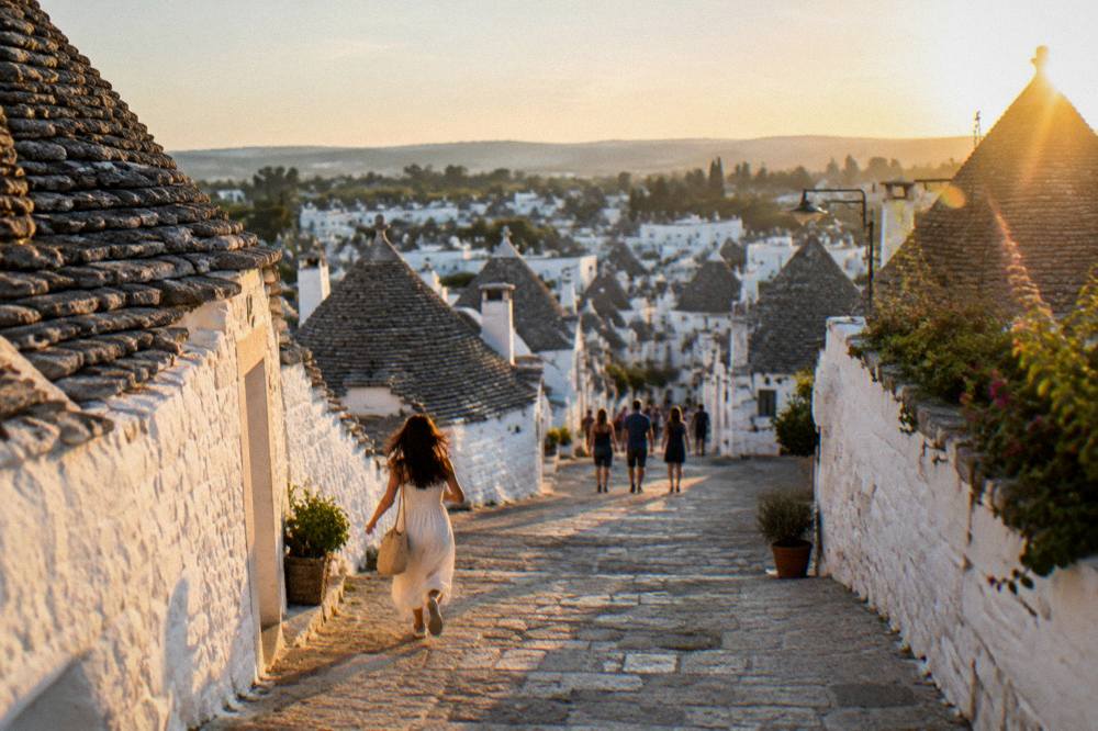 A panoramic view over a hillside of trulli roofs at golden hour