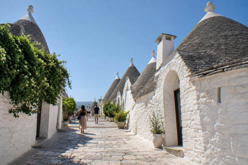 Rows of conical white stone trulli houses on a sunlit street