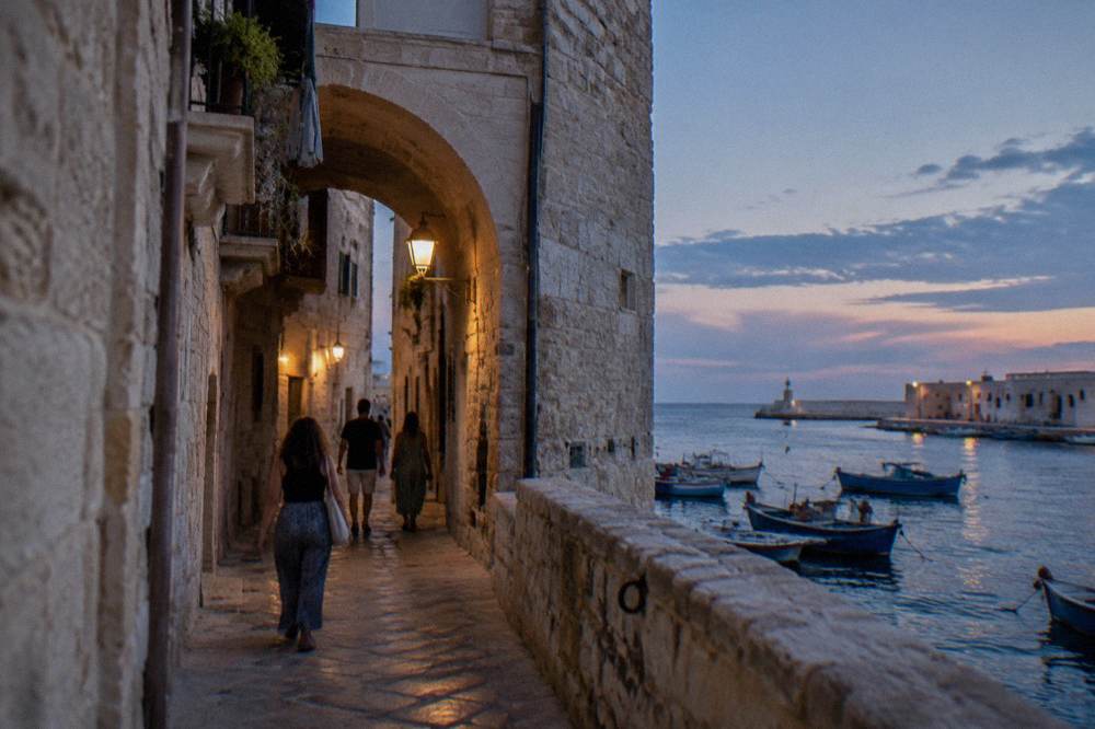 People walking through a narrow arched alley in an old Italian quarter