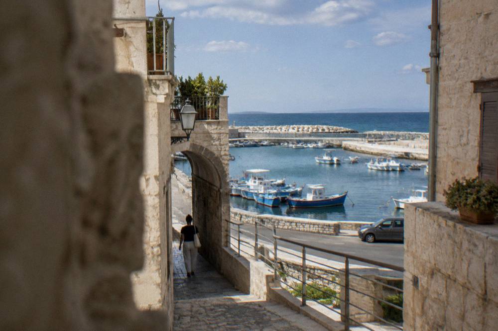 A car on a coastal road with open countryside and sea in the distance
