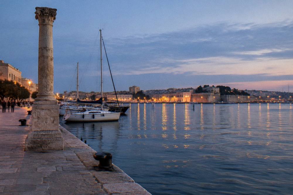 An evening view across a harbour inlet with lights reflecting on the water and boats at rest