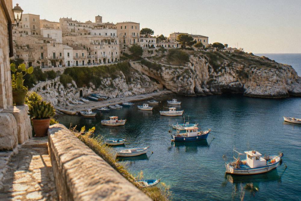 The small marina of Castro below limestone cliffs with fishing boats moored in clear water