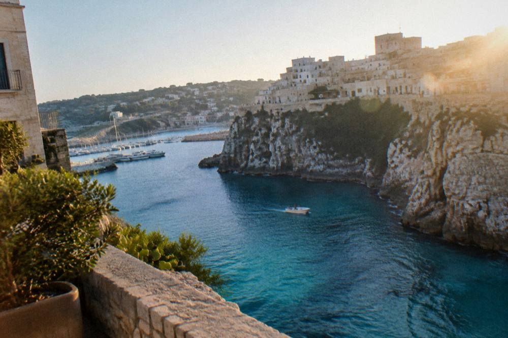 Clear turquoise water at the base of limestone cliffs with a small boat passing