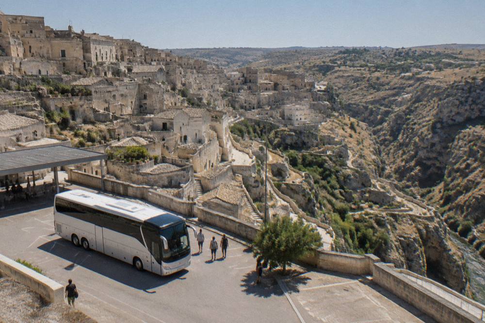 A long-distance coach parked at a small Italian bus terminal in morning light